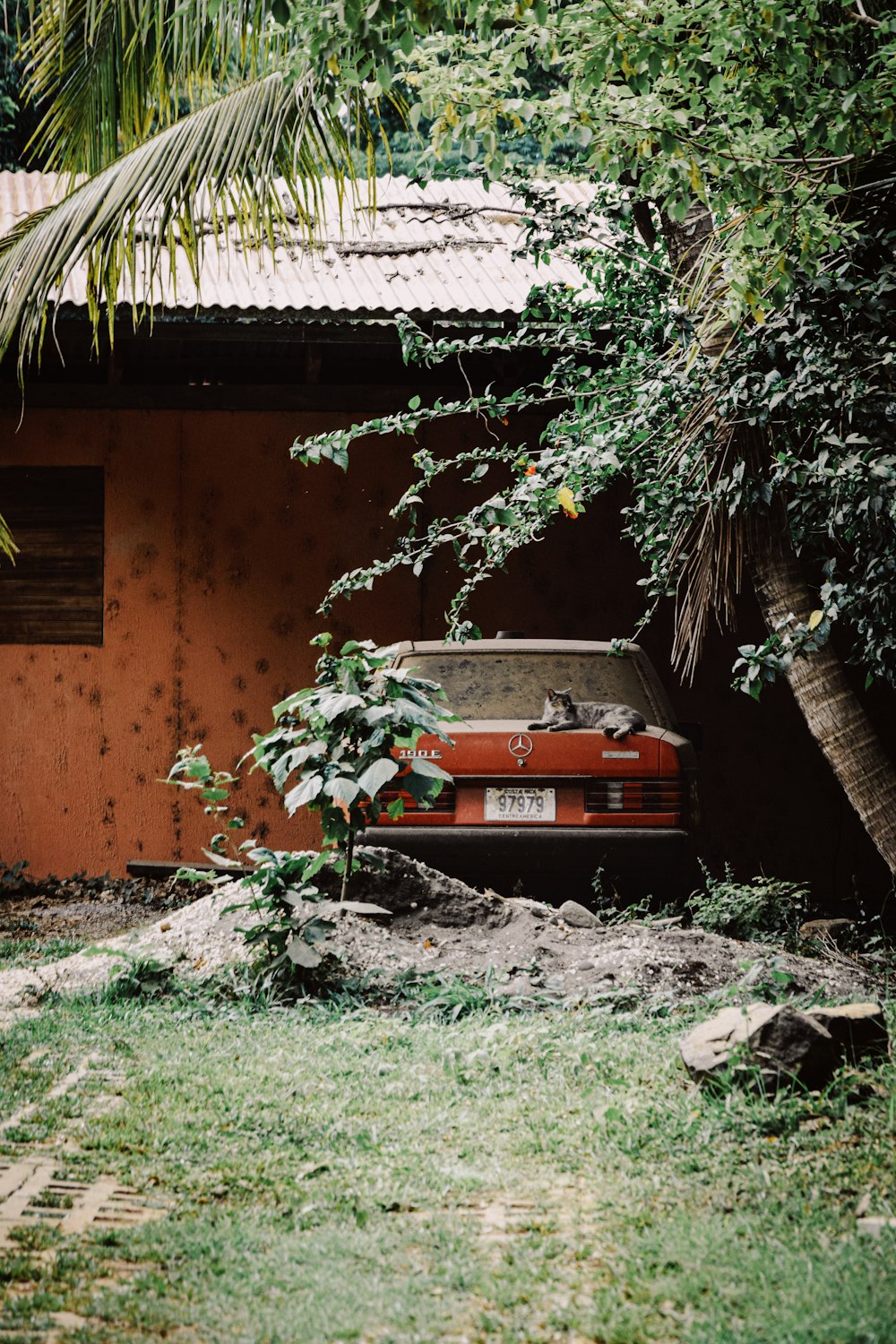 red car parked beside brown concrete house during daytime