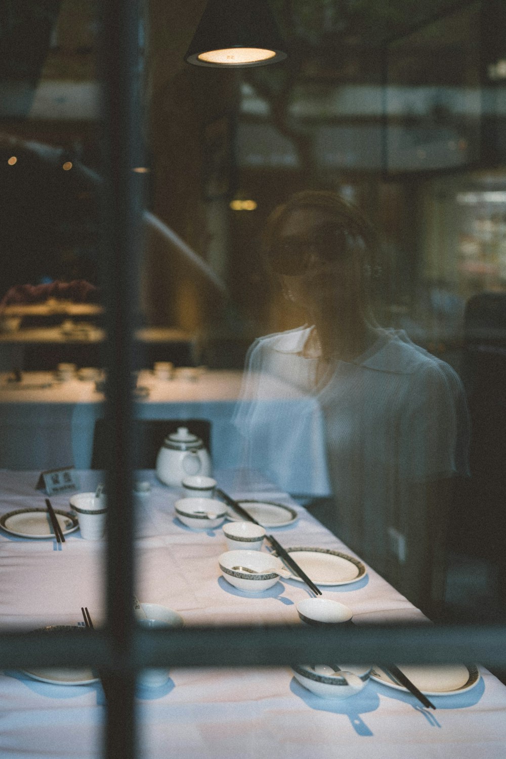 woman in white long sleeve shirt sitting beside table