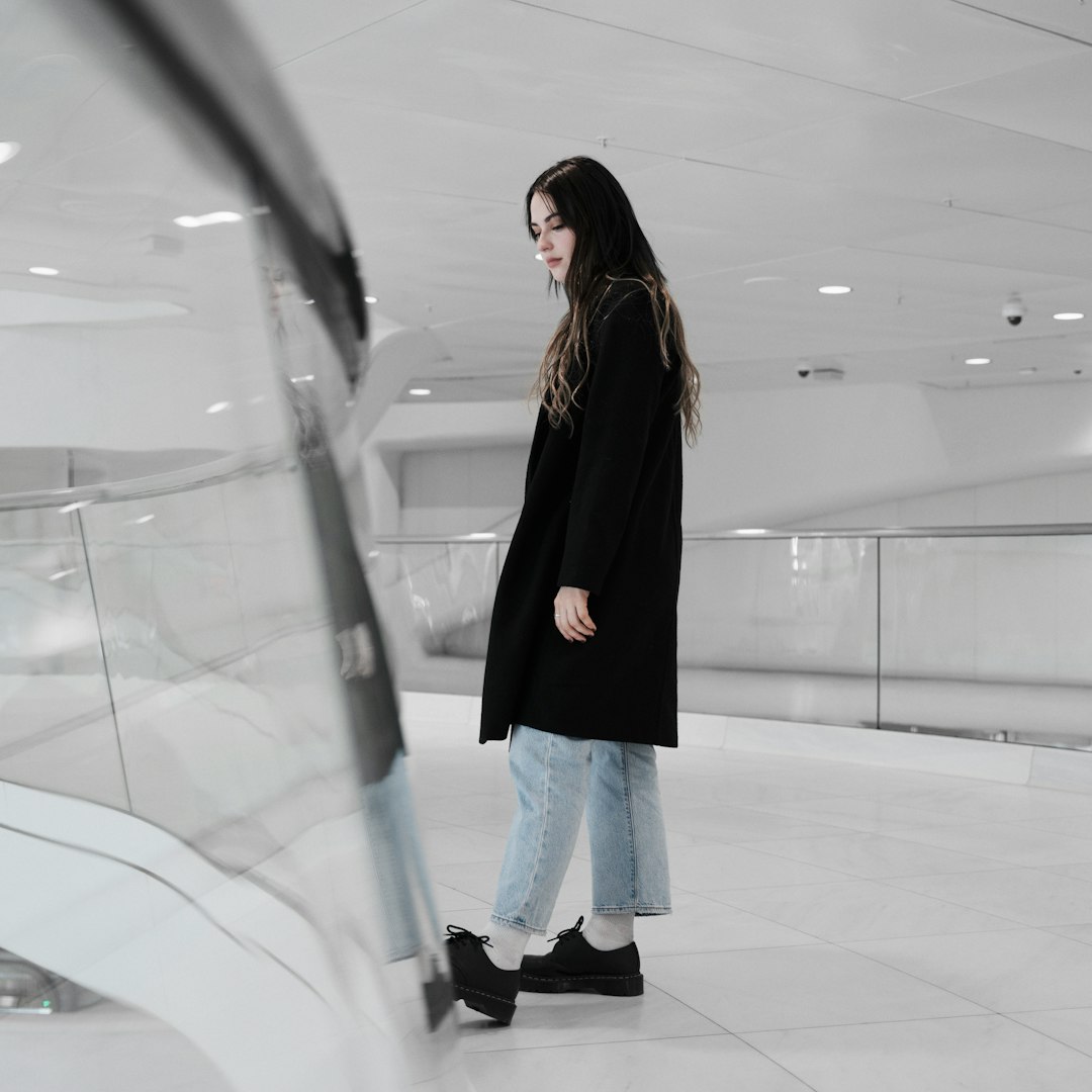 woman in black long sleeve shirt and blue denim jeans standing inside building