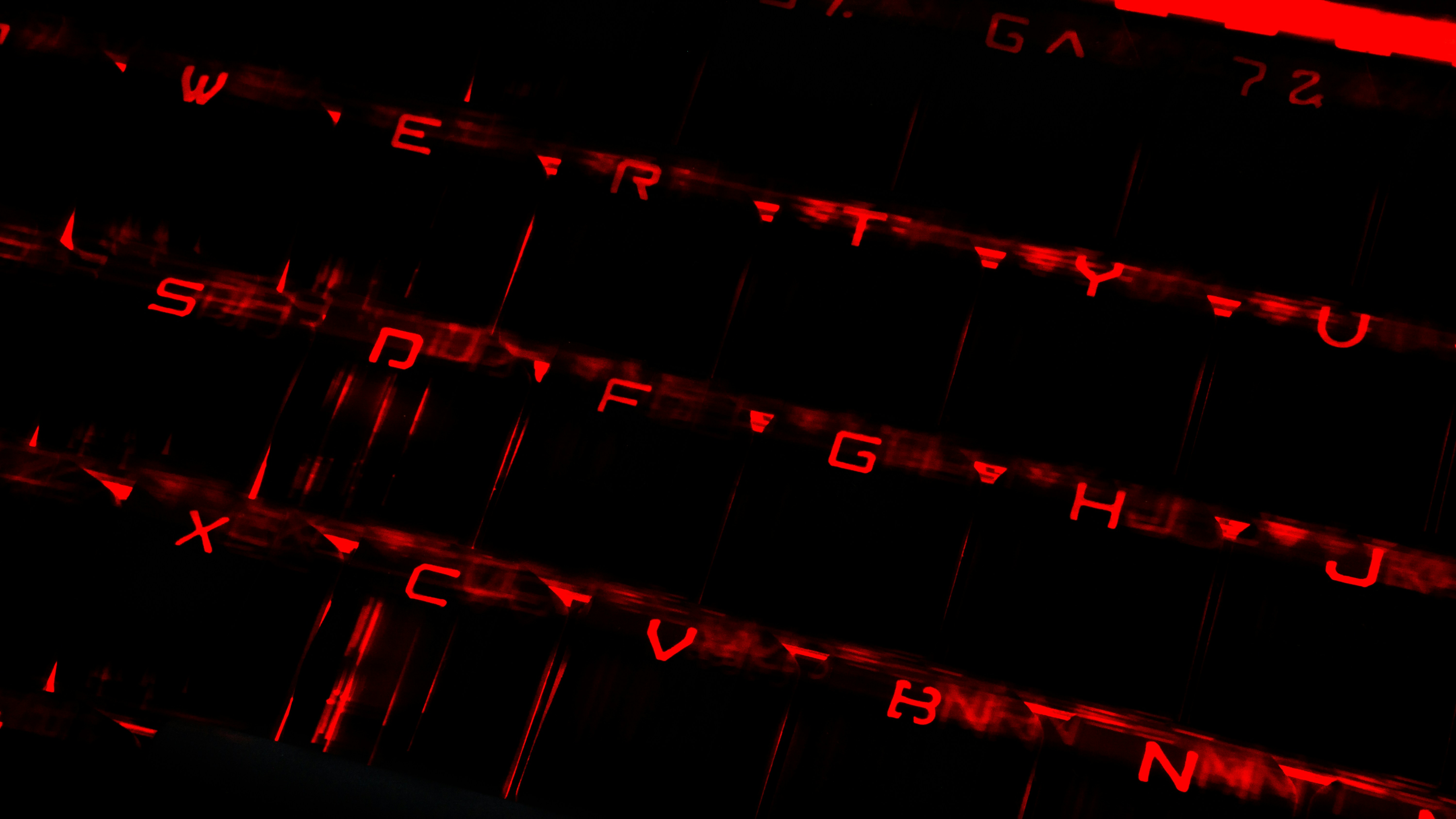 Glowing neon gaming keyboard and setup with dark atmospheric background and red accents
