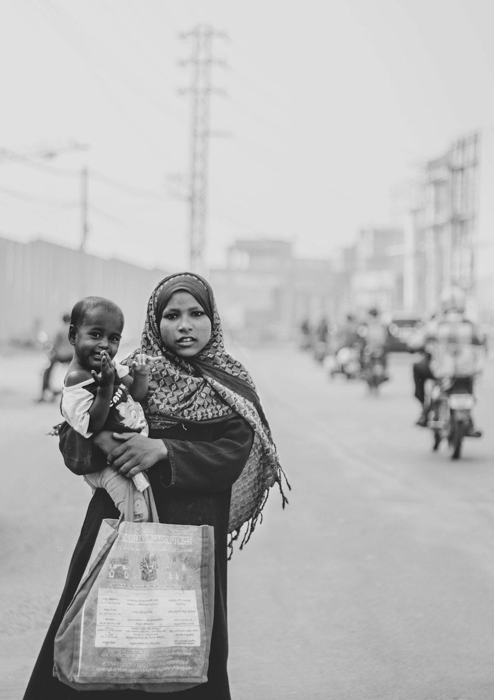 grayscale photo of woman in scarf and scarf holding glass bottle