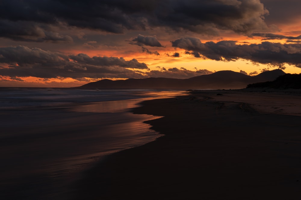 body of water under cloudy sky during sunset