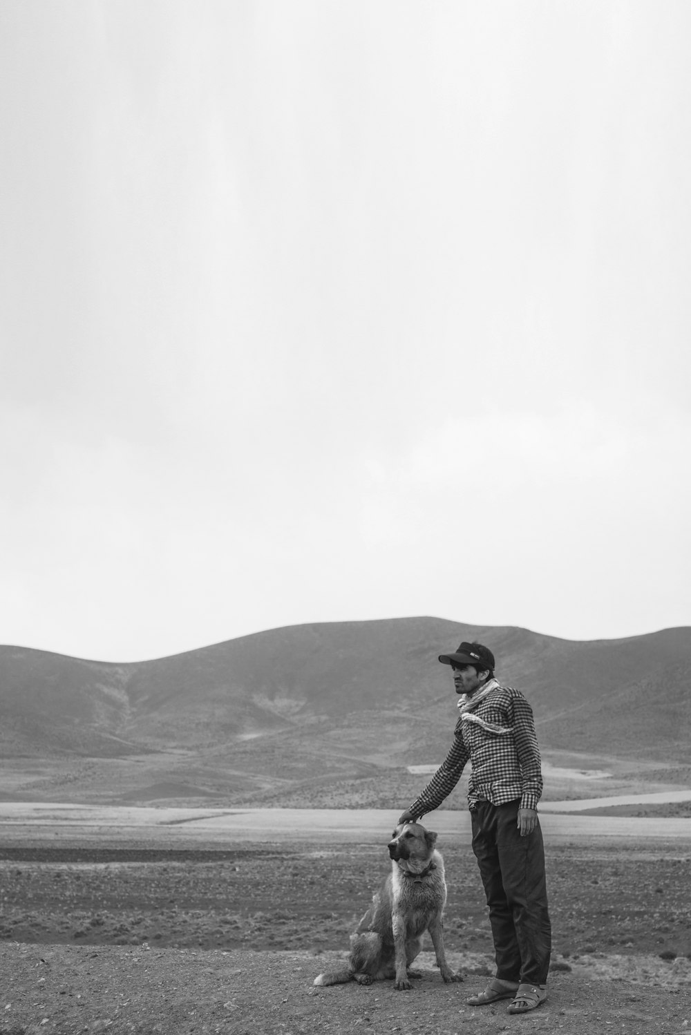 海岸に立っている黒いジャケットとズボンの男のグレースケール写真