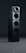 A sleek black audio speaker with a modern, minimalist design. The speaker consists of two stacked rectangular units, each featuring circular sound outputs. The top unit has a prominent cone-like speaker, while the bottom unit includes two additional circular drivers. The surface has a glossy finish, reflecting light subtly.