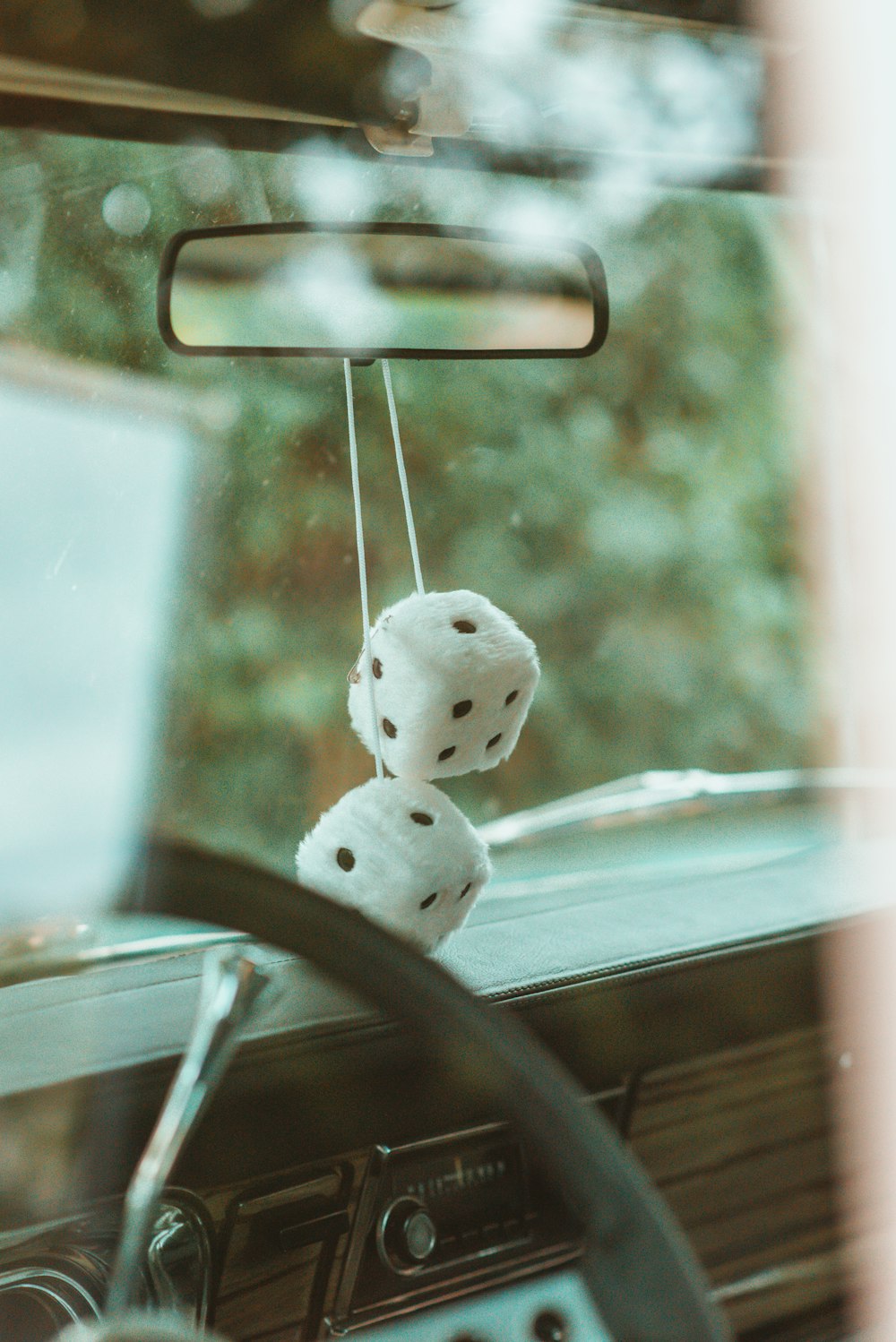 white and black plush toy on car rear mirror