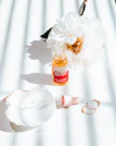 A serene scene of a rose-hued serum bottle beside fresh petals and a gold spoon.