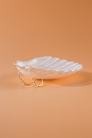 A pair of gold hoop earrings with subtle engraved details on a soft beige background.