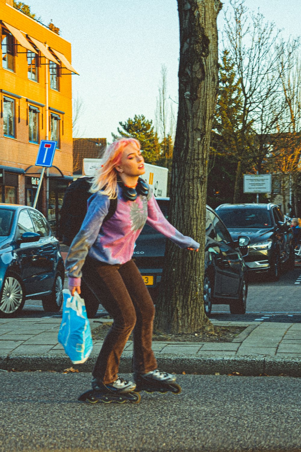 ピンクの長袖シャツとブルーのデニムのショートパンツを着た女性が昼間、歩道に立っている