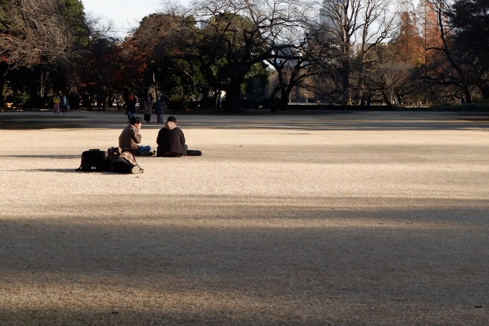 2 person sitting on brown sand during daytime