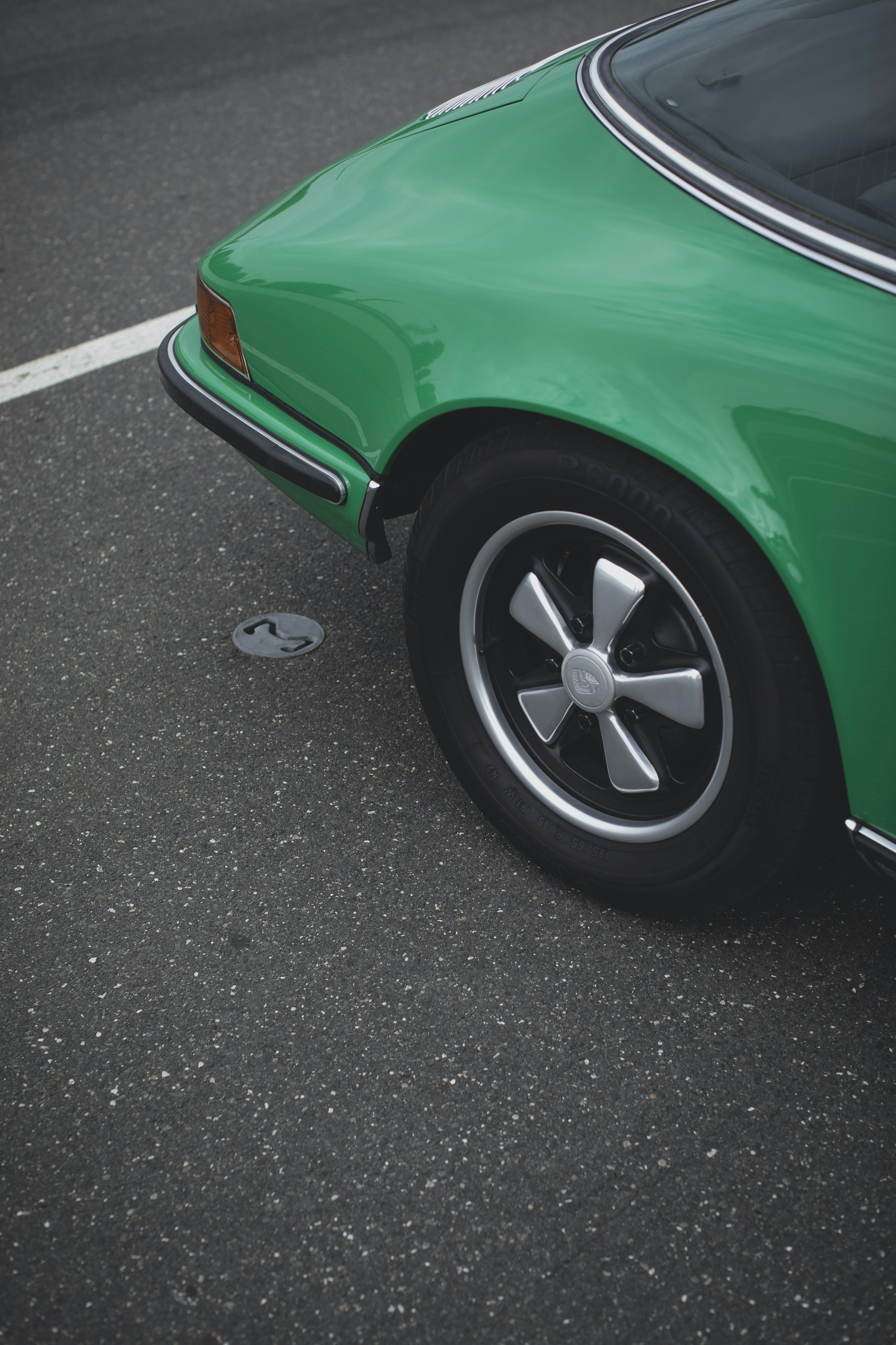 green car on gray asphalt road during daytime