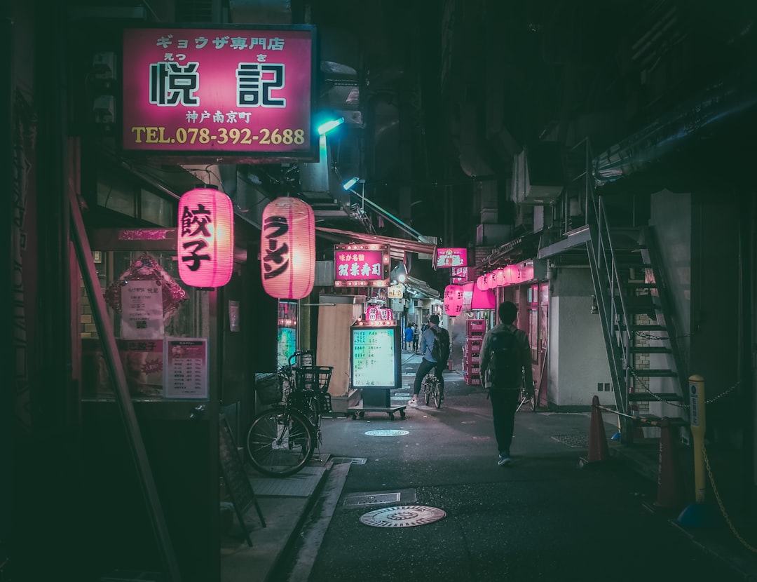 man in black jacket walking on sidewalk during night time