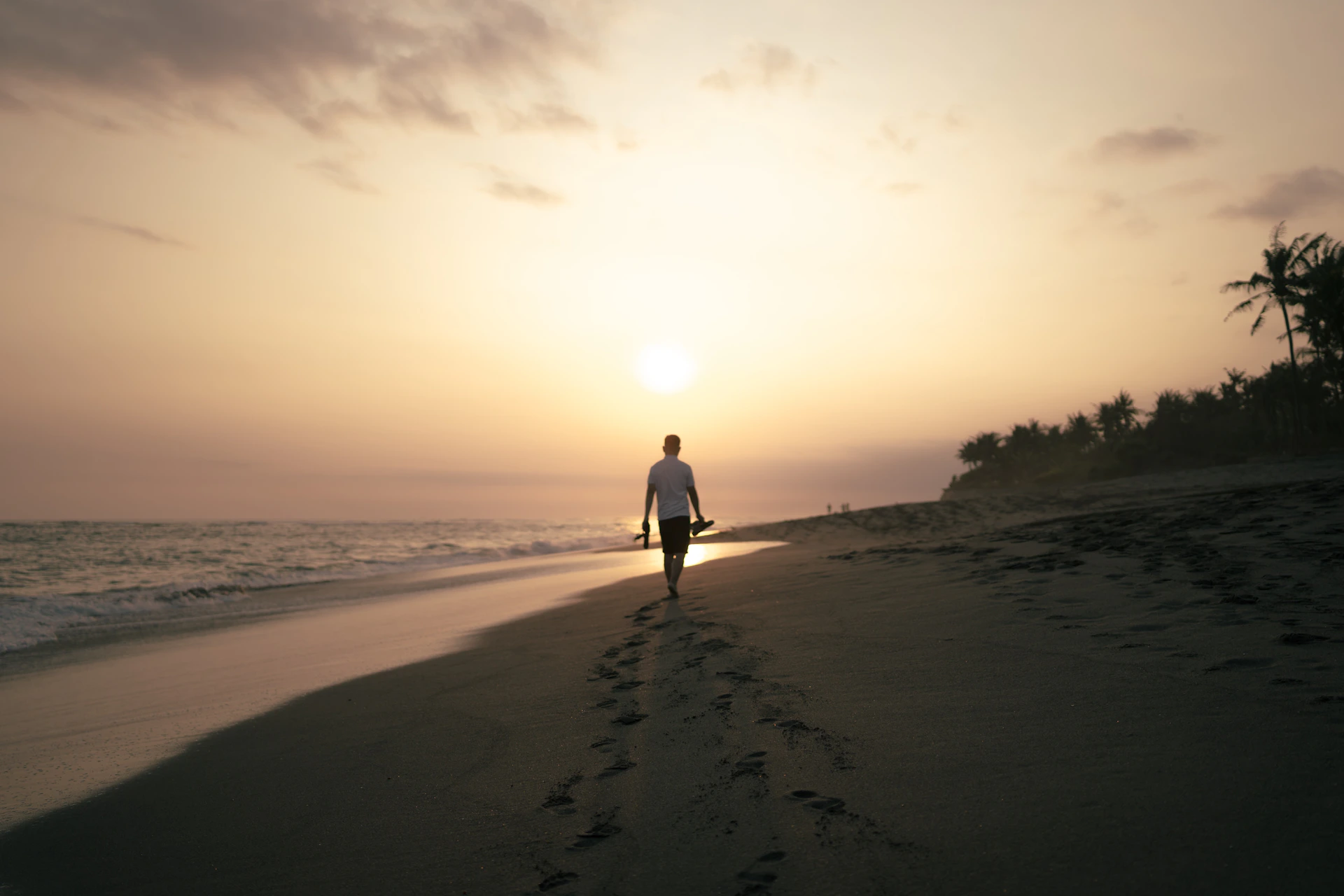 man and woman walking on beach during sunset