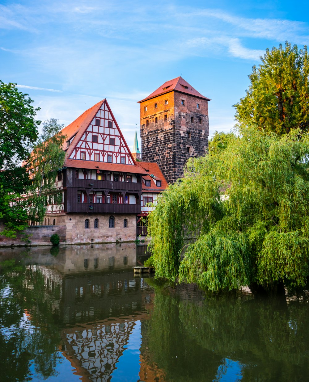 brown brick building beside green trees and body of water during daytime