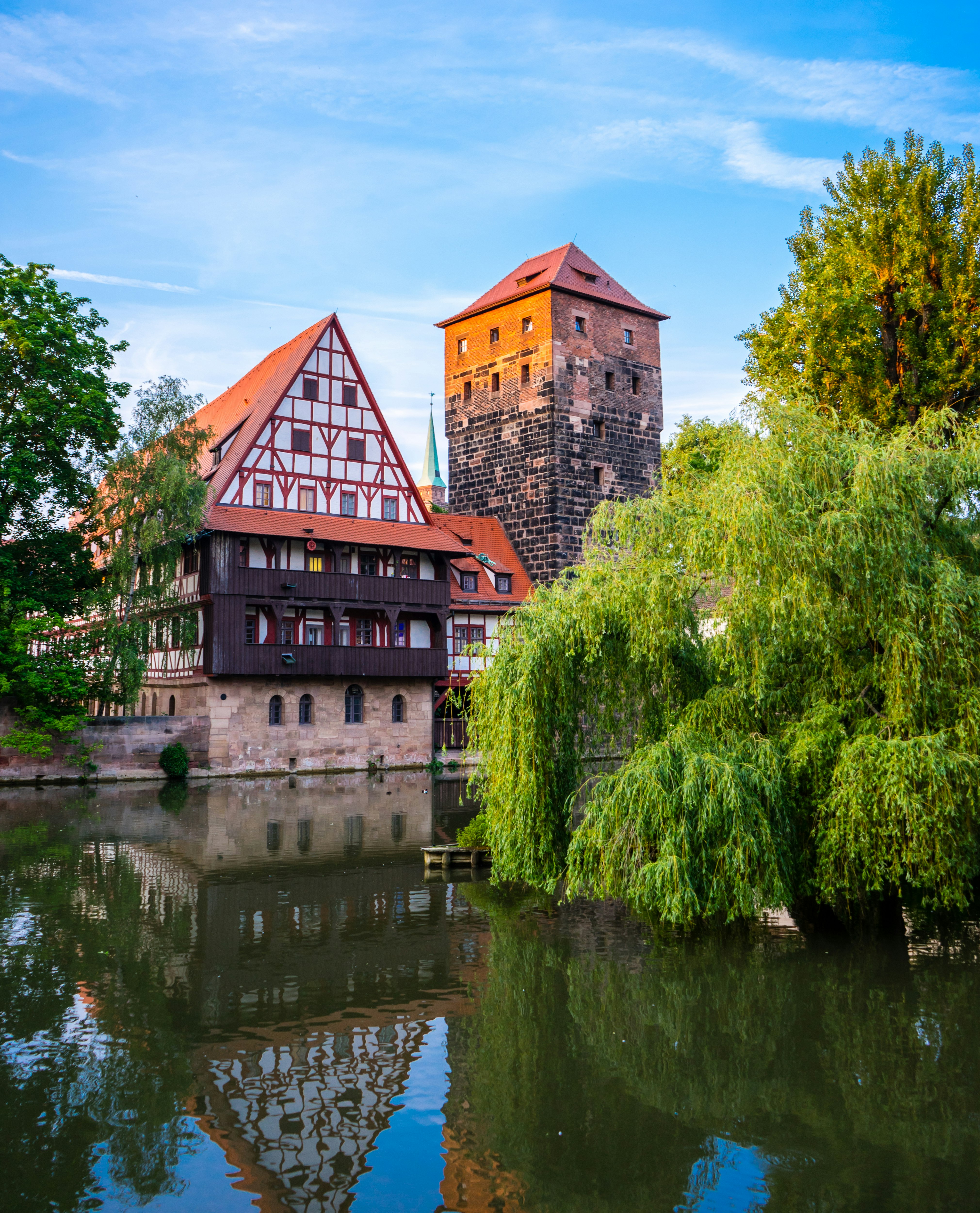 brown brick building beside green trees and body of water during daytime