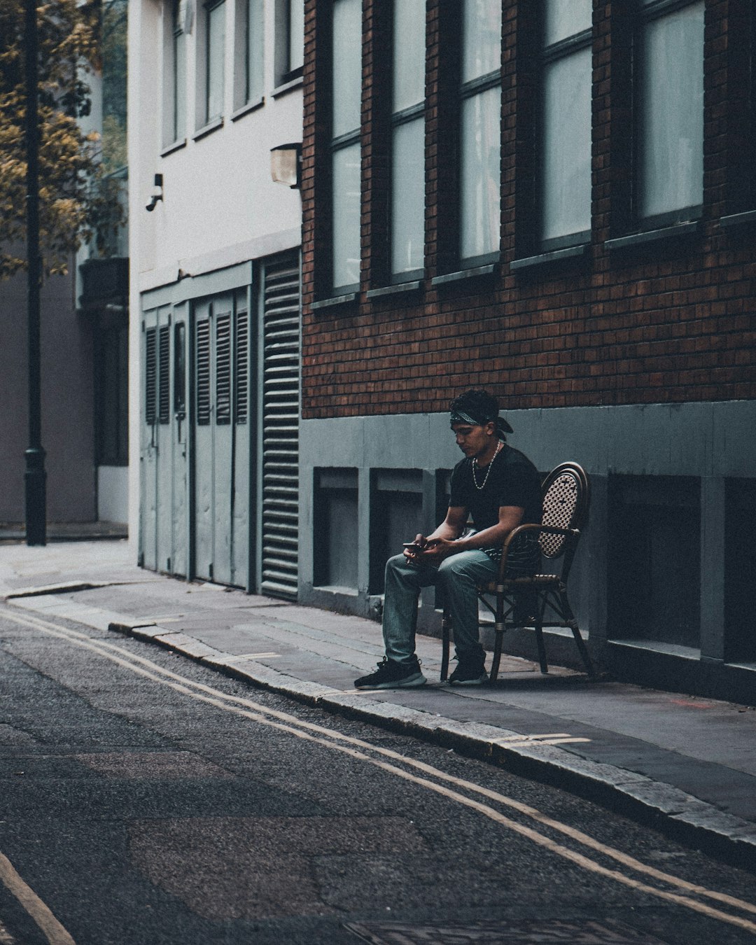 man in blue shirt sitting on black metal bench near brown concrete building during daytime