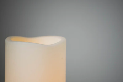 Close-up of a creamy white candle with delicate textures, set against a rustic wooden background.
