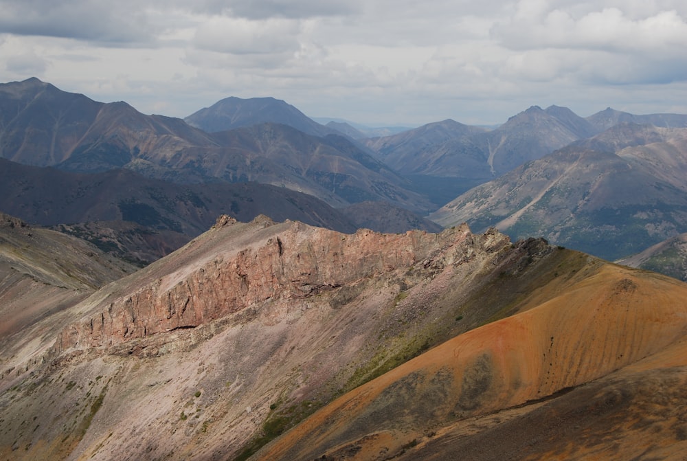 brown and green mountains under white clouds and blue sky during daytime