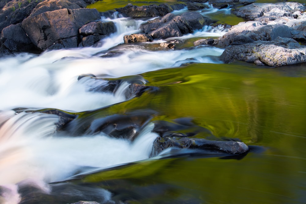 water falls on rocky shore during daytime