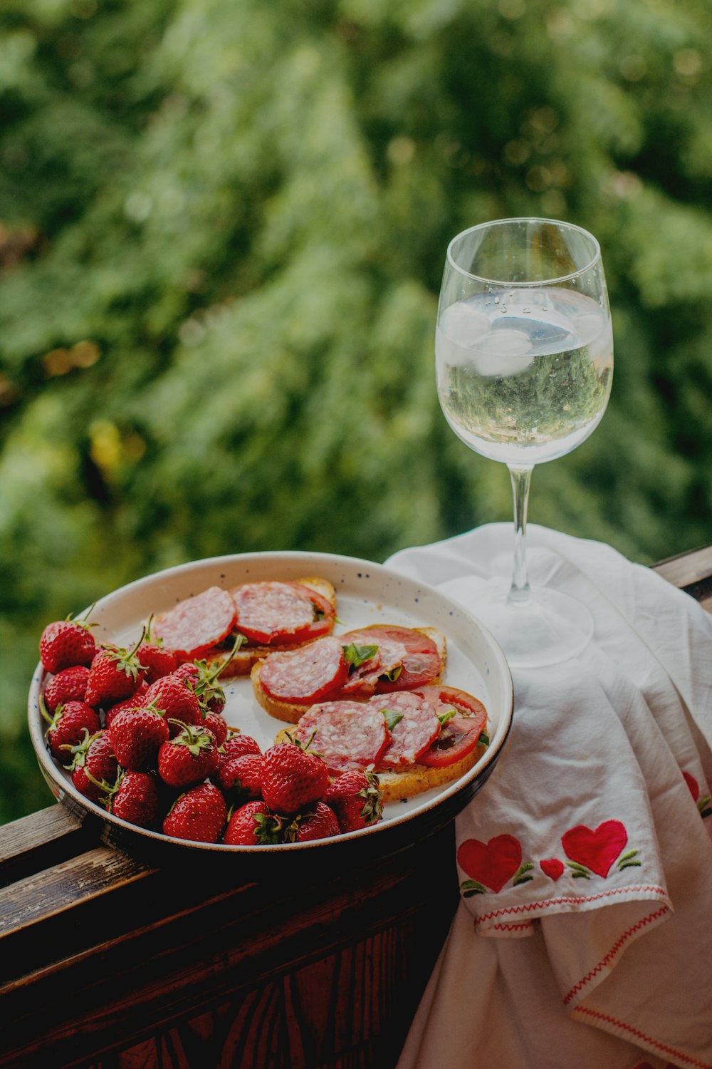 strawberries in bowl beside wine glass on table