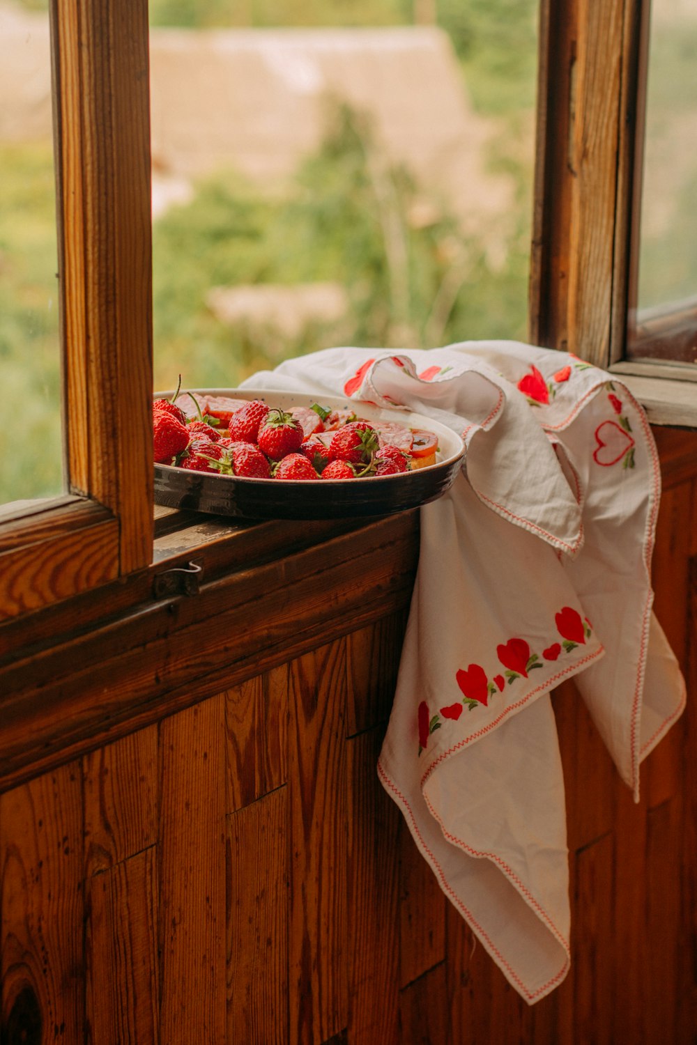 a plate of strawberries on a window sill