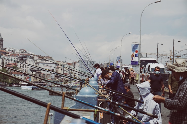a group of people standing on a pier next to a body of water