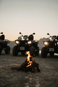 A group of off-roaders gathered around a campfire sharing stories at sunset.