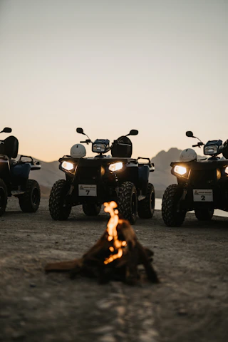 A group of off-roaders gathered around a campfire sharing stories at sunset.