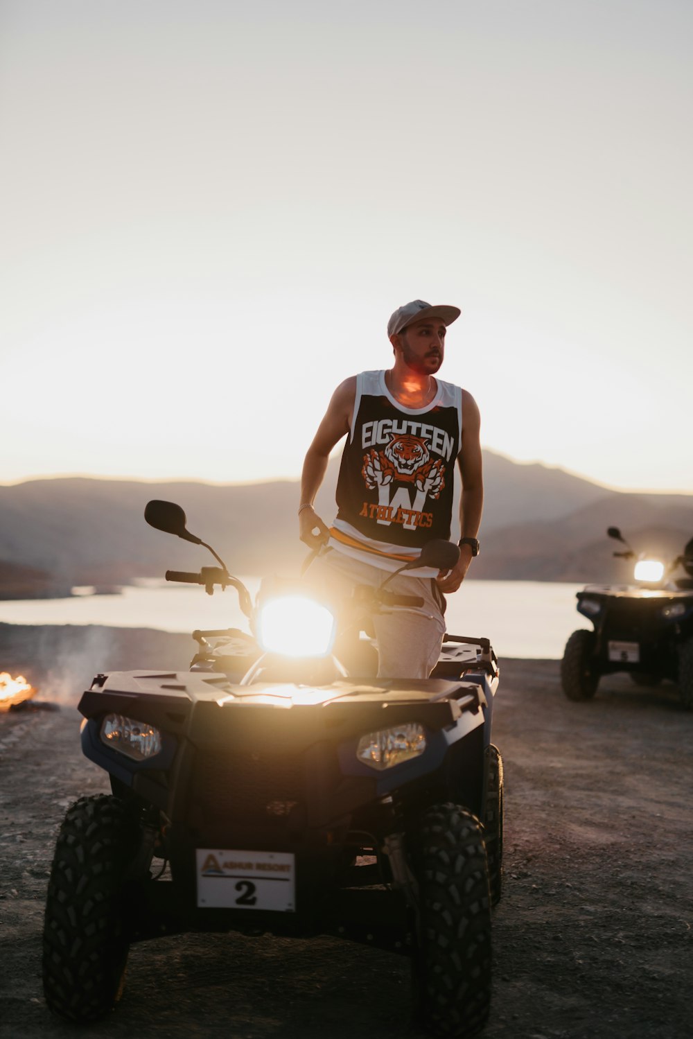 man in black and white tank top sitting on black motorcycle during sunset