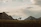 Traveler on horseback crossing the Gobi desert with dramatic clouds overhead.