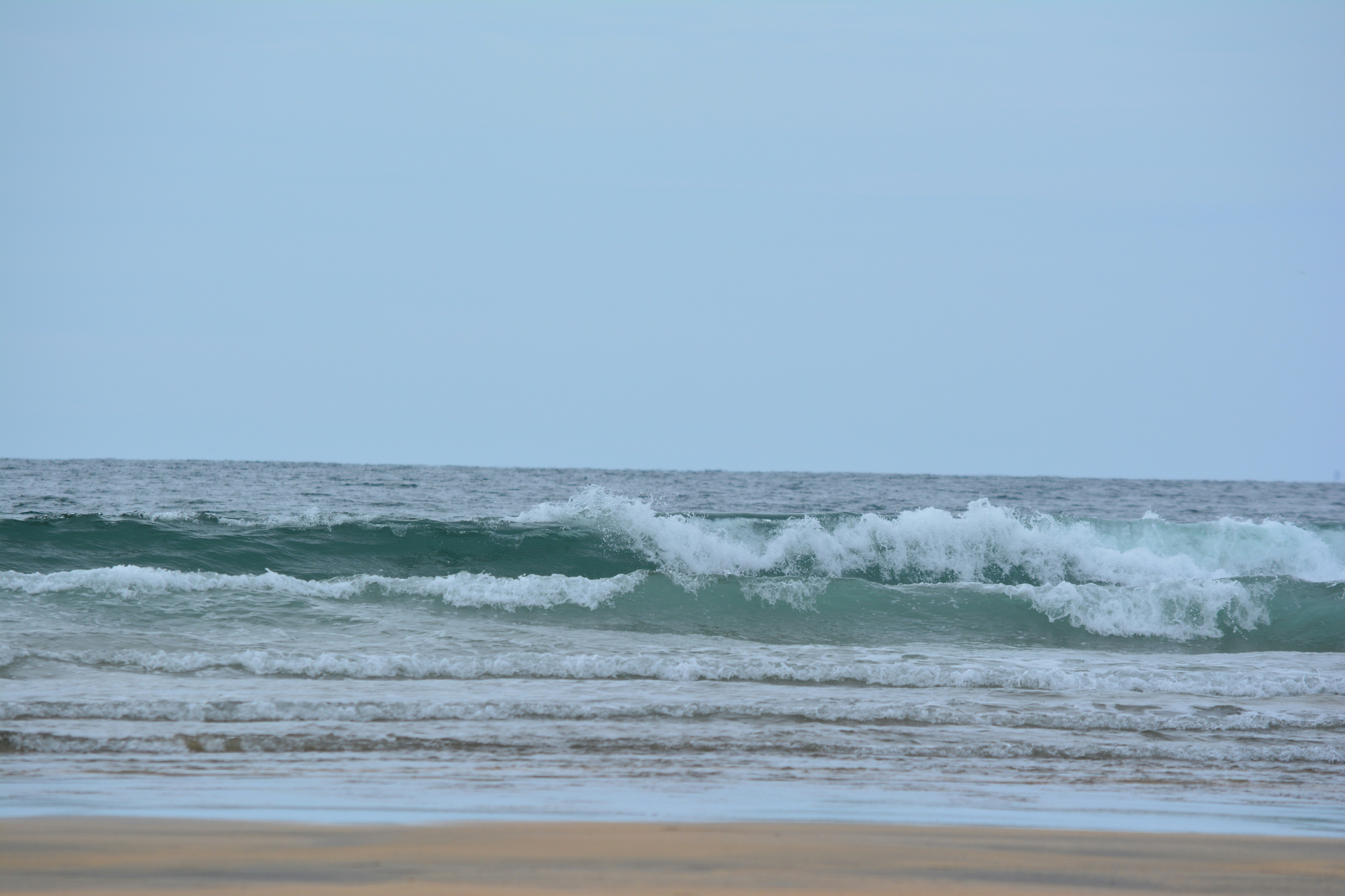 ocean waves crashing on shore during daytime