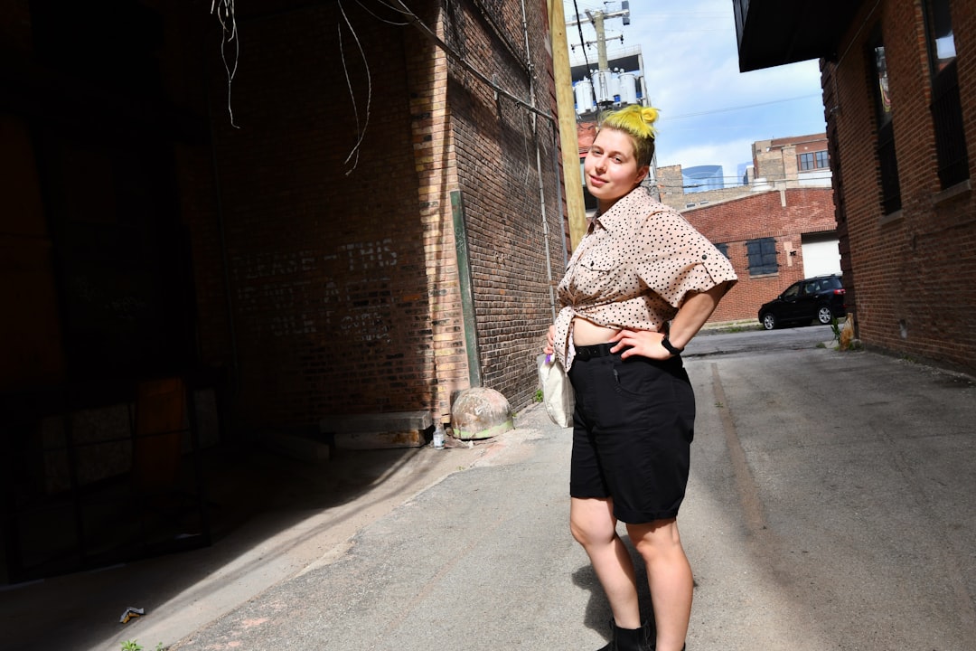 woman in black and white long sleeve shirt and black skirt standing on sidewalk during daytime