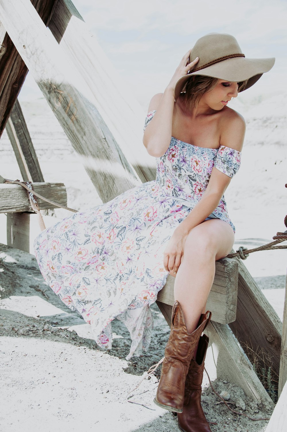 woman in white and blue floral spaghetti strap dress sitting on brown wooden chair