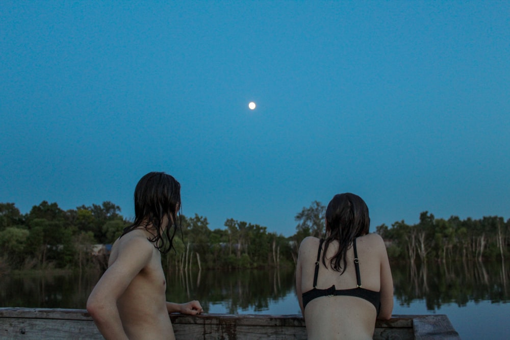 woman in black bikini bottom standing near body of water during daytime