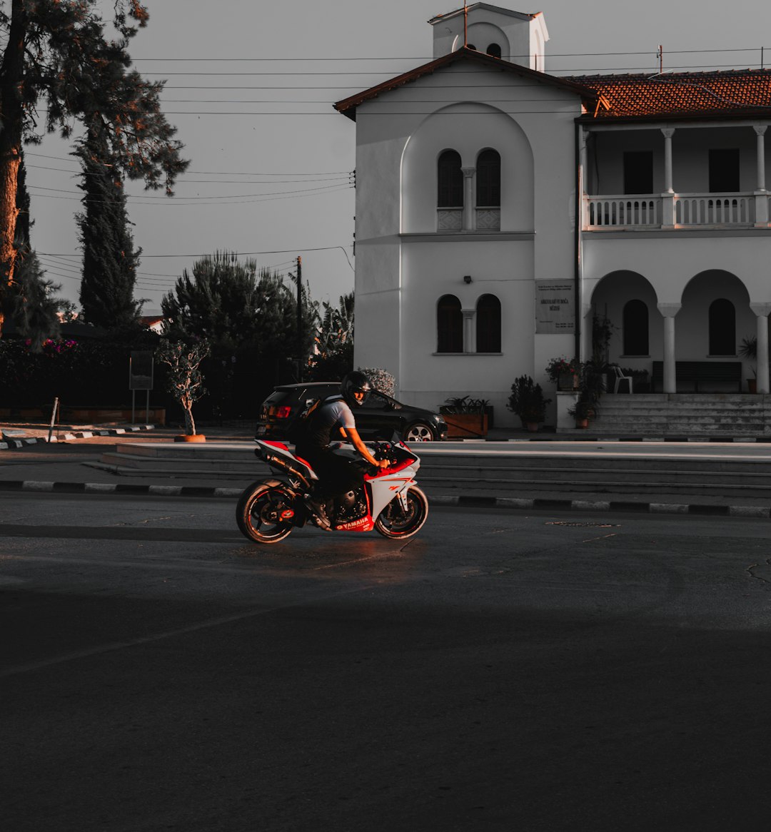 man riding motorcycle on road near white concrete building during daytime