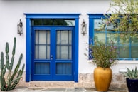 Exterior of a bright blue house with a newly painted front door and trim.