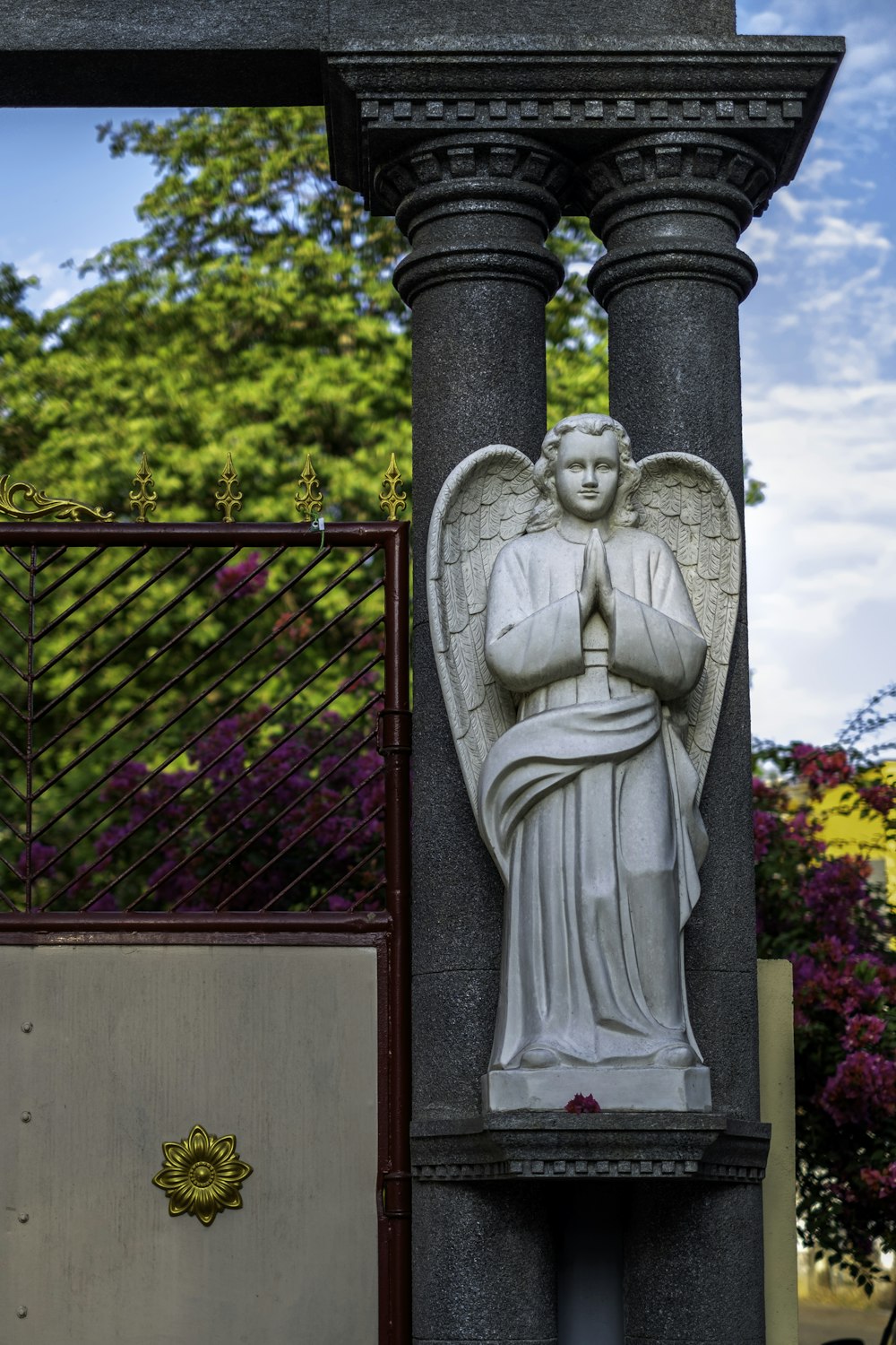 angel statue near red metal gate