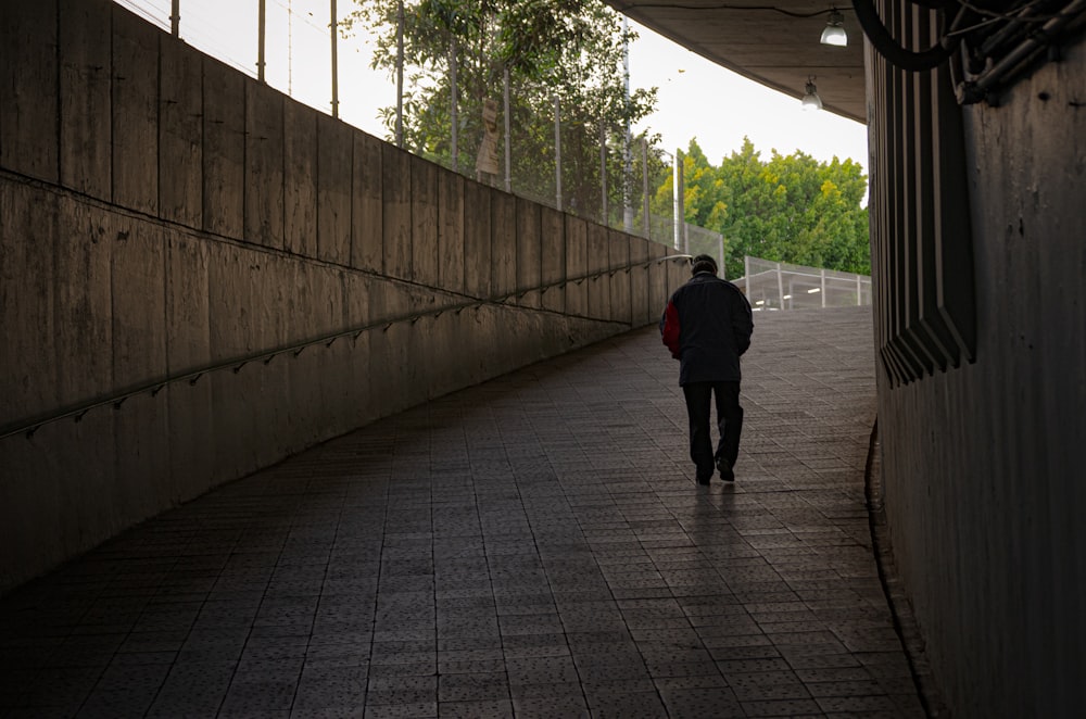 man in black jacket walking on sidewalk during daytime