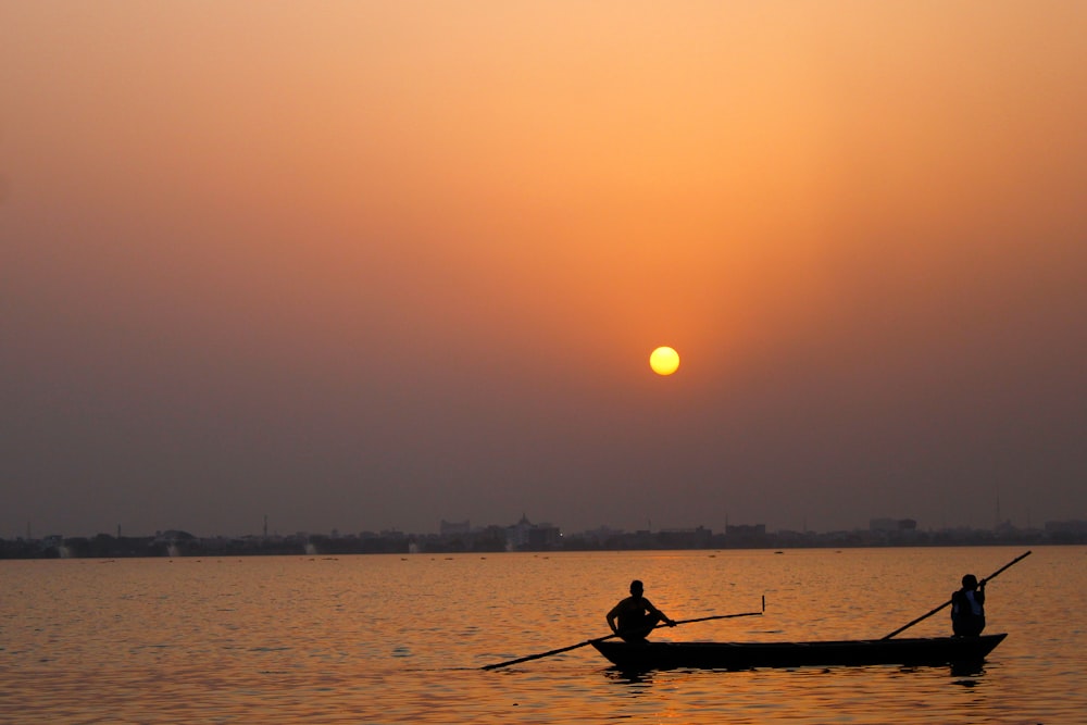 Silueta del hombre que monta en el barco durante la puesta del sol