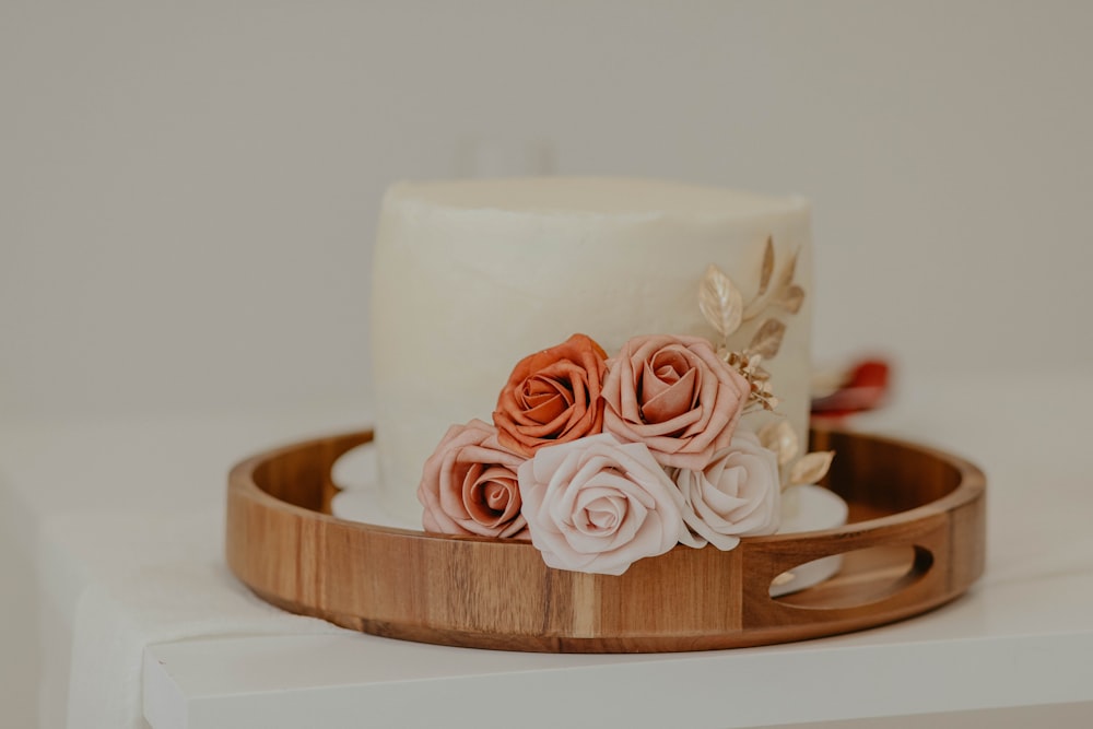 weißer und rosa Rosenkuchen auf braunem runden Holztablett