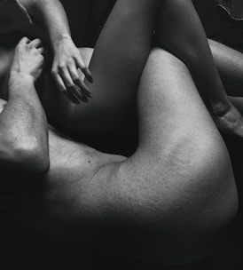 The black and white photo features two intertwined human bodies, focusing on their limbs and torsos. The composition emphasizes intimacy and connection through close physical contact.