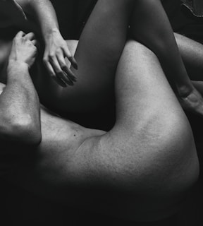 The black and white photo features two intertwined human bodies, focusing on their limbs and torsos. The composition emphasizes intimacy and connection through close physical contact.