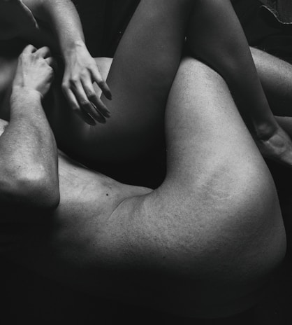 The black and white photo features two intertwined human bodies, focusing on their limbs and torsos. The composition emphasizes intimacy and connection through close physical contact.