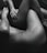 The black and white photo features two intertwined human bodies, focusing on their limbs and torsos. The composition emphasizes intimacy and connection through close physical contact.