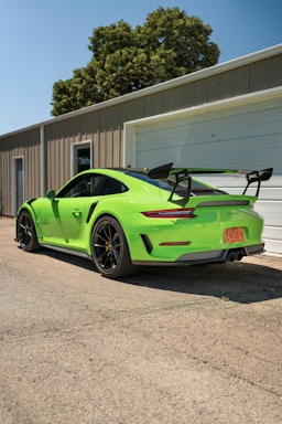 green porsche 911 parked near white building
