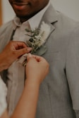 A candid shot of the groom adjusting his tie with a silver boutonniere.