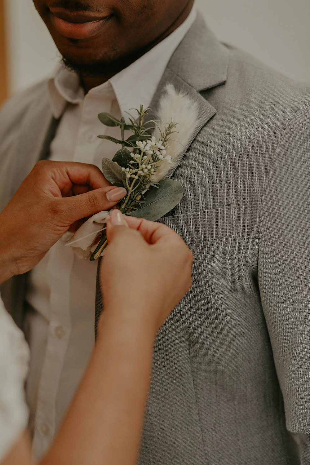 Hombre con traje gris sosteniendo una rosa blanca