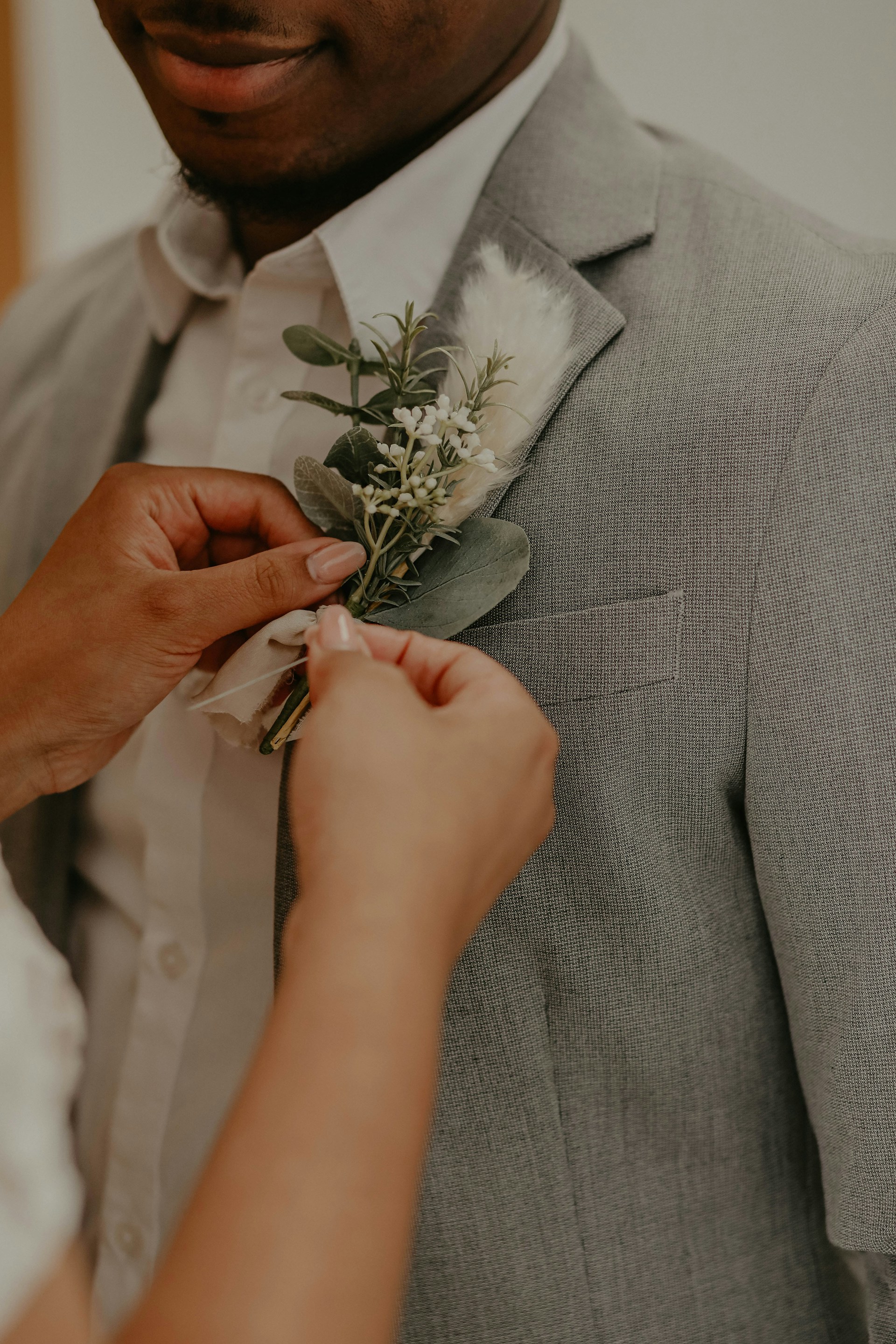 man in gray suit holding white rose