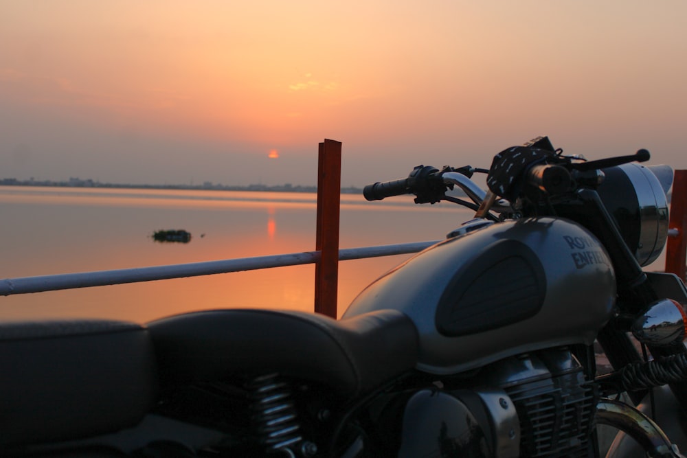 black motorcycle parked beside brown wooden fence during sunset