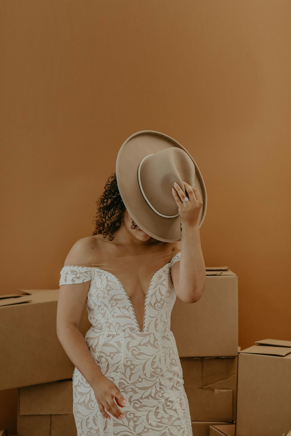 woman in white floral tank top holding brown hat