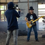 man in blue hoodie playing yellow electric guitar